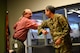 A photo of an airman and a civilian sharing an elbow "high-five"