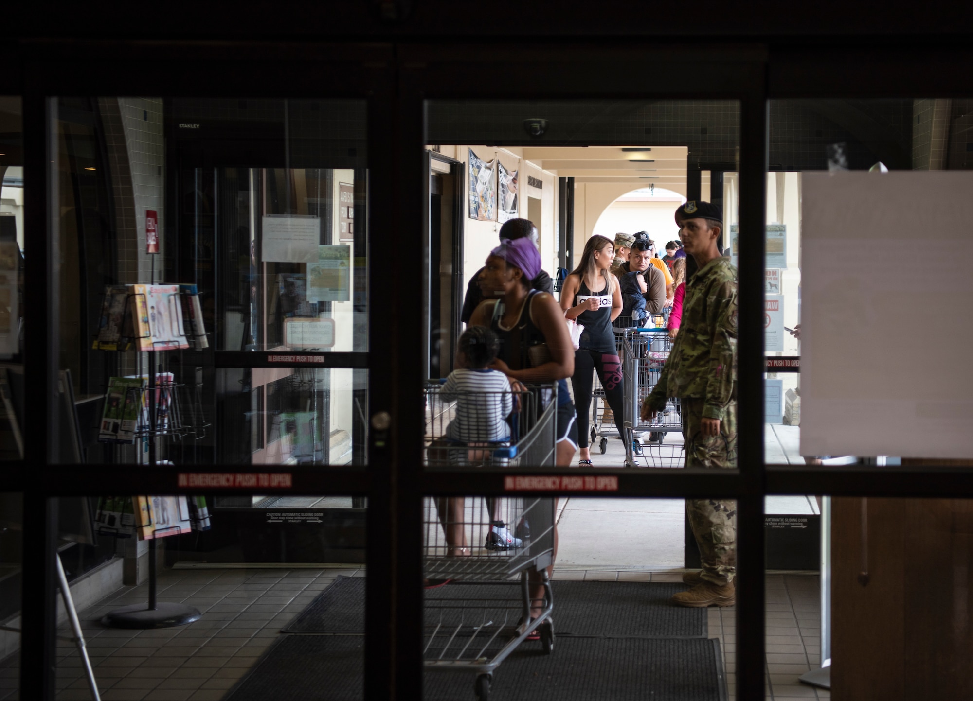 Service members and spouses assigned to Andersen Air Force Base and Naval Base Guam wait in line to enter the Andersen Commissary at AAFB, Guam, March 17, 2020.