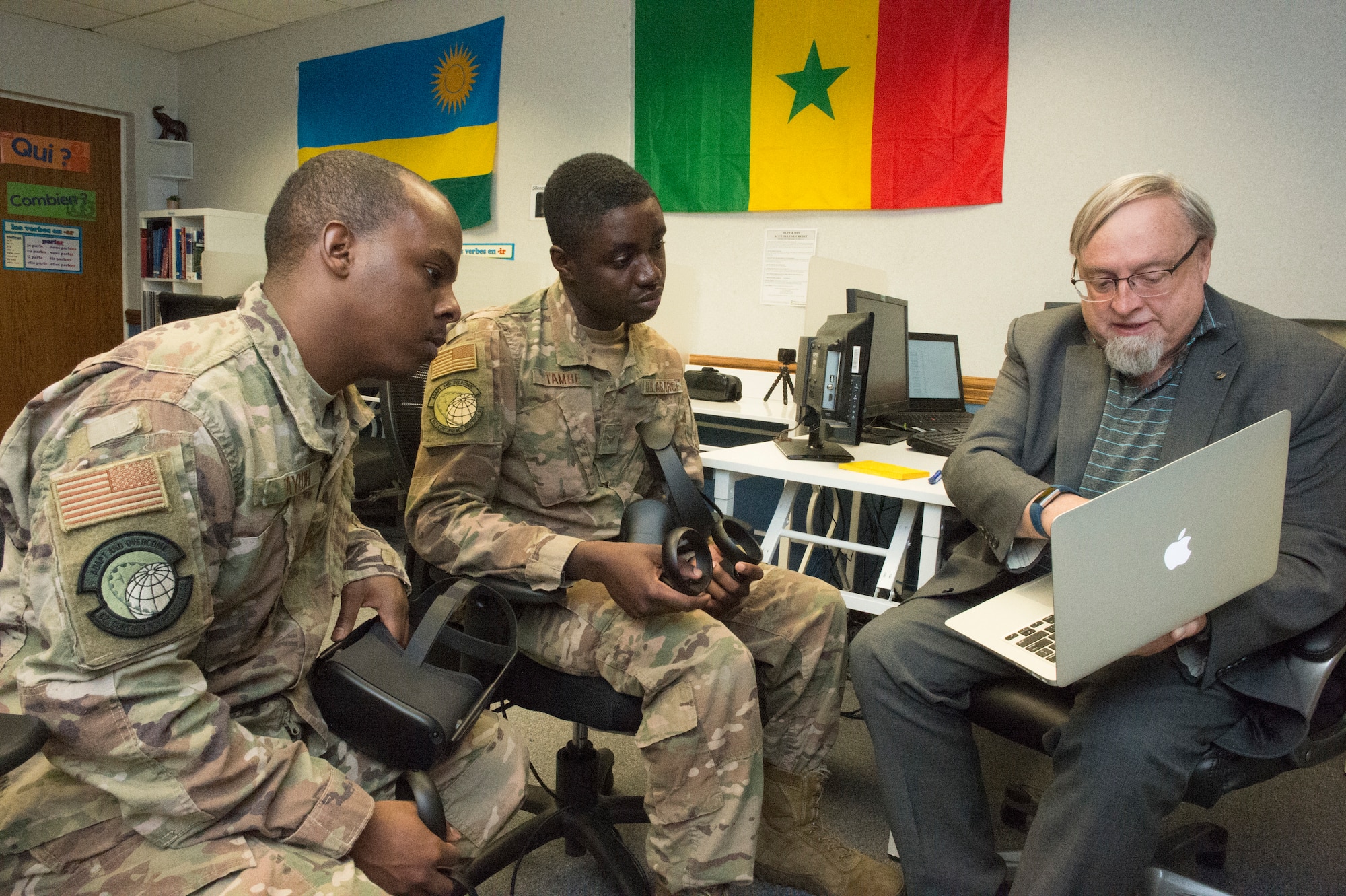 Adrian Clive (right), 818th Mobility Support Advisory Squadron command language education program manager, explains future plans for the Language Learning Center with Airman 1st Class Etchy Tambe (middle) and Senior Airman Trevaughn Taylor (left), 621st Contingency Response Squadron aerial porter journeymen, at Joint Base McGuire-Dix-Lakehurst, New Jersey, Mar. 3, 2020. The LLC offers traditional and unique ways to brush up on French, including books, board games, study booths, French TV shows and virtual reality games. (U.S. Air Force photo by Staff Sgt. Sarah Brice)