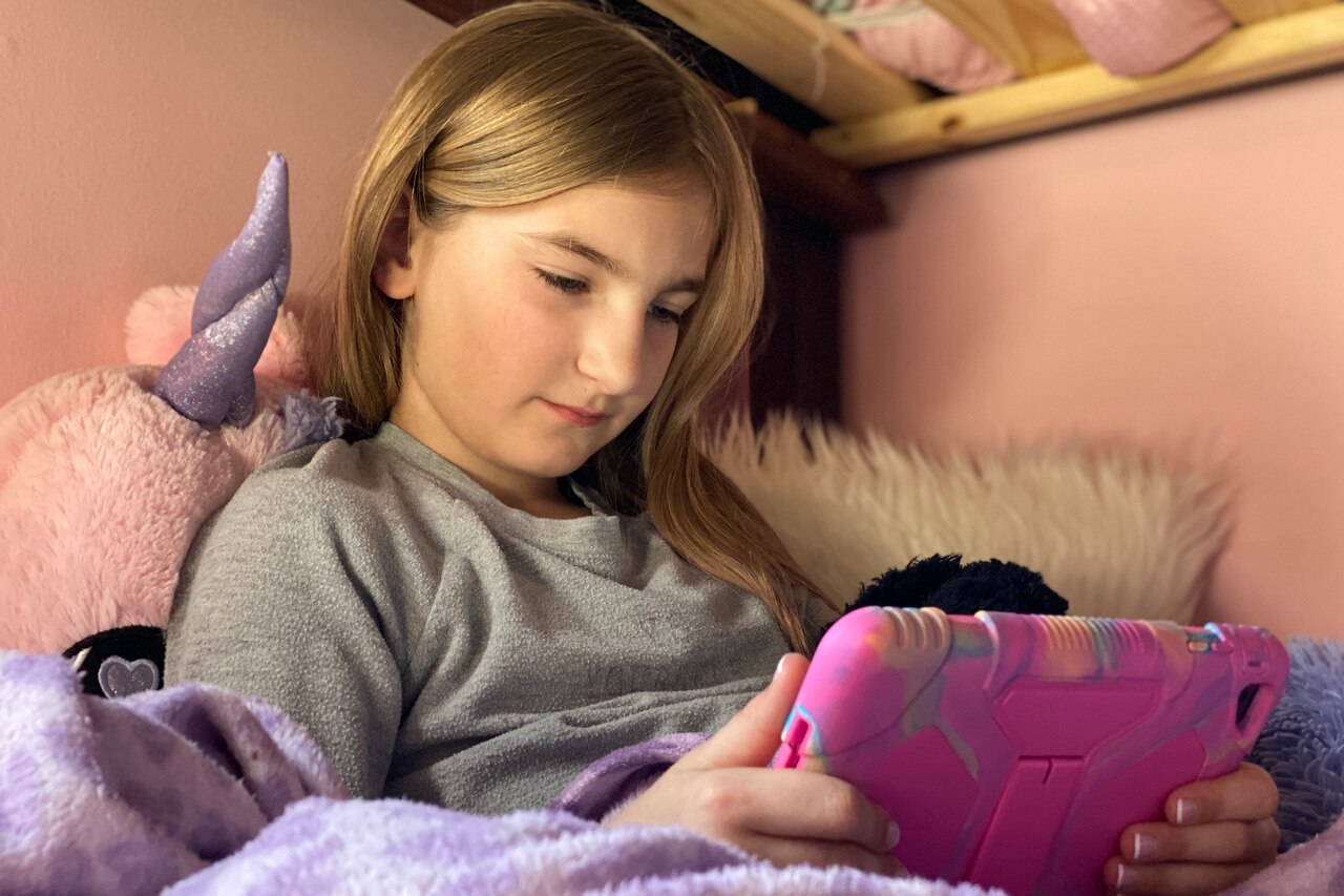 A girl looks at an electronic screen device.