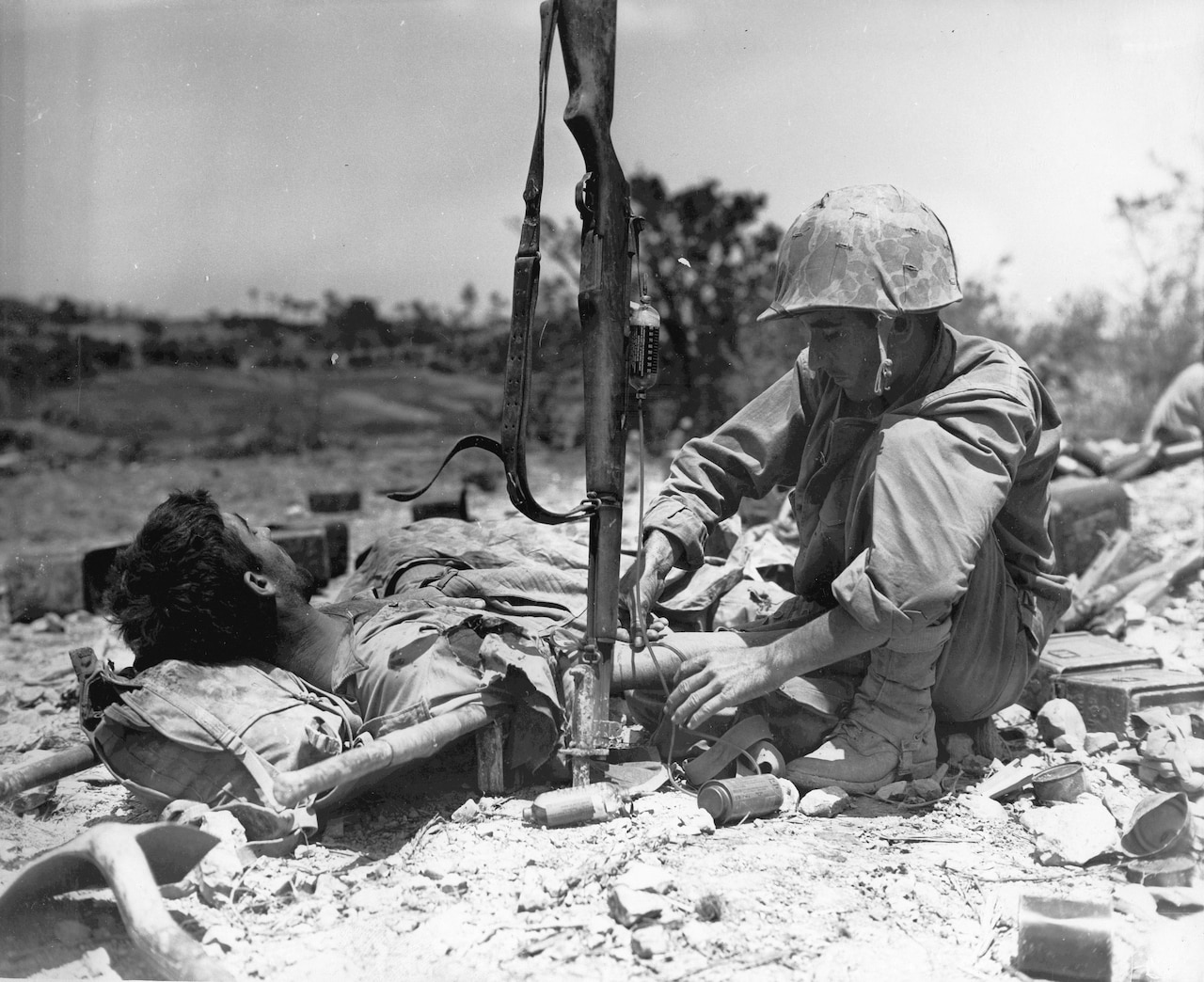 A wounded serviceman is attended by another service member.