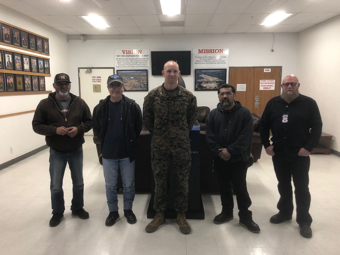 (Left) Paul Flores, Heavy Mobile Equipmenet Mechanic; Kazuyoshi Brooks, Machinist; Salazar Salvador, Mobile Equipmenet Metal Mechanic; and Mike Johnson, Machinist Supervisor; stand with Col. Craig C. Clemans, base commander, as he recognized the Production Plant Barstow, Marine Depot Maintenance Command, artisans whom restored the plaques on two base landmarks, presenting them with the Commander's Challenge coin on the Yermo Annex aboard Marine Corps Logistics Base Barstow, Calif. March 12. (Photo courtesy PPB, MDMC).