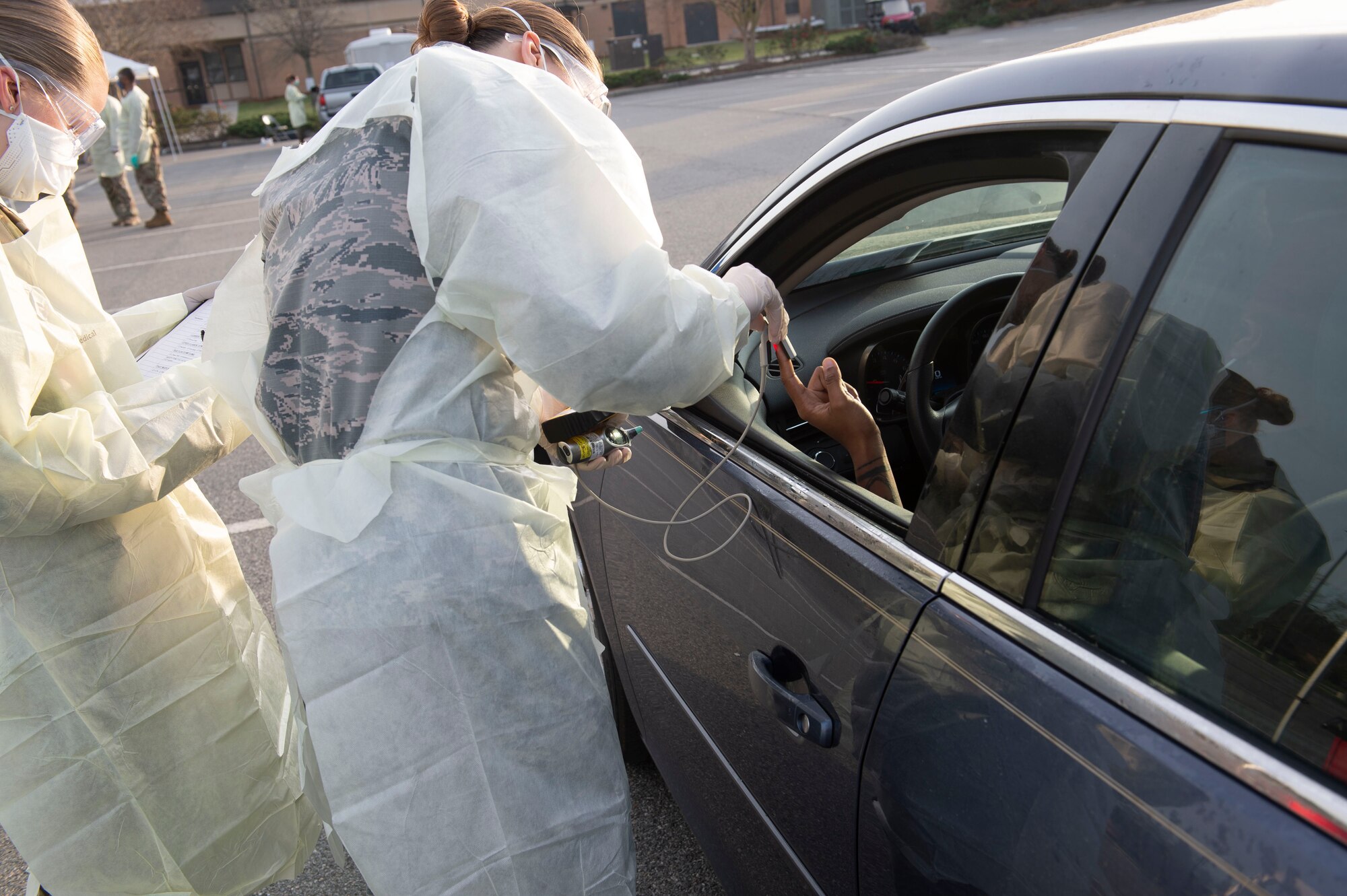 Photo of Airmen screening an active duty Airman during a drive-through health screening.