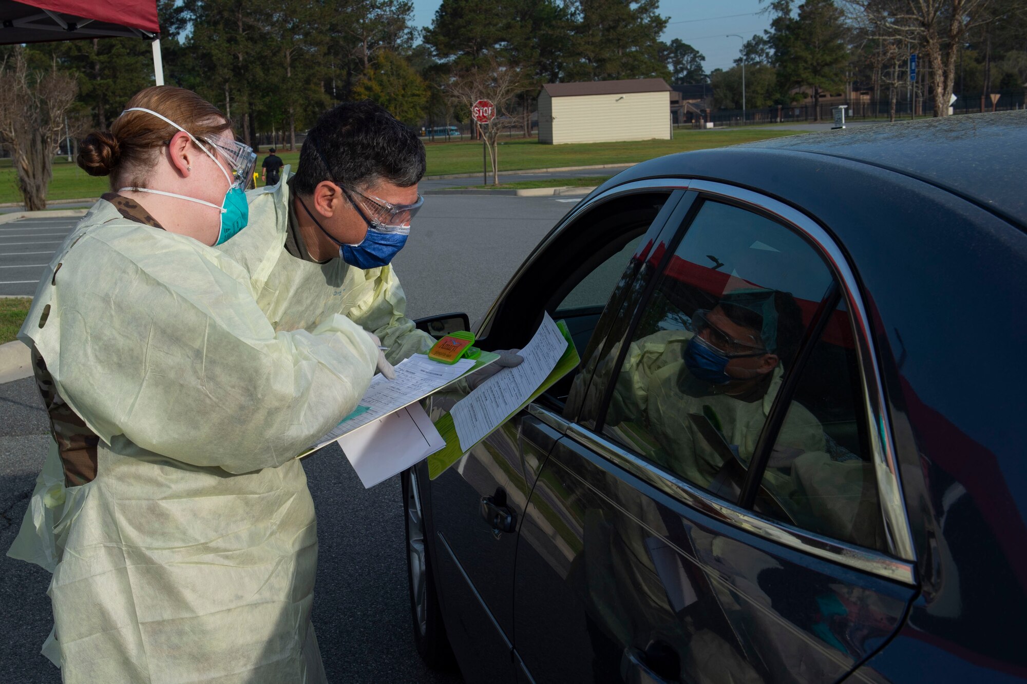 Photo of Airmen asking an active duty Airman questions during a drive-through health screening.