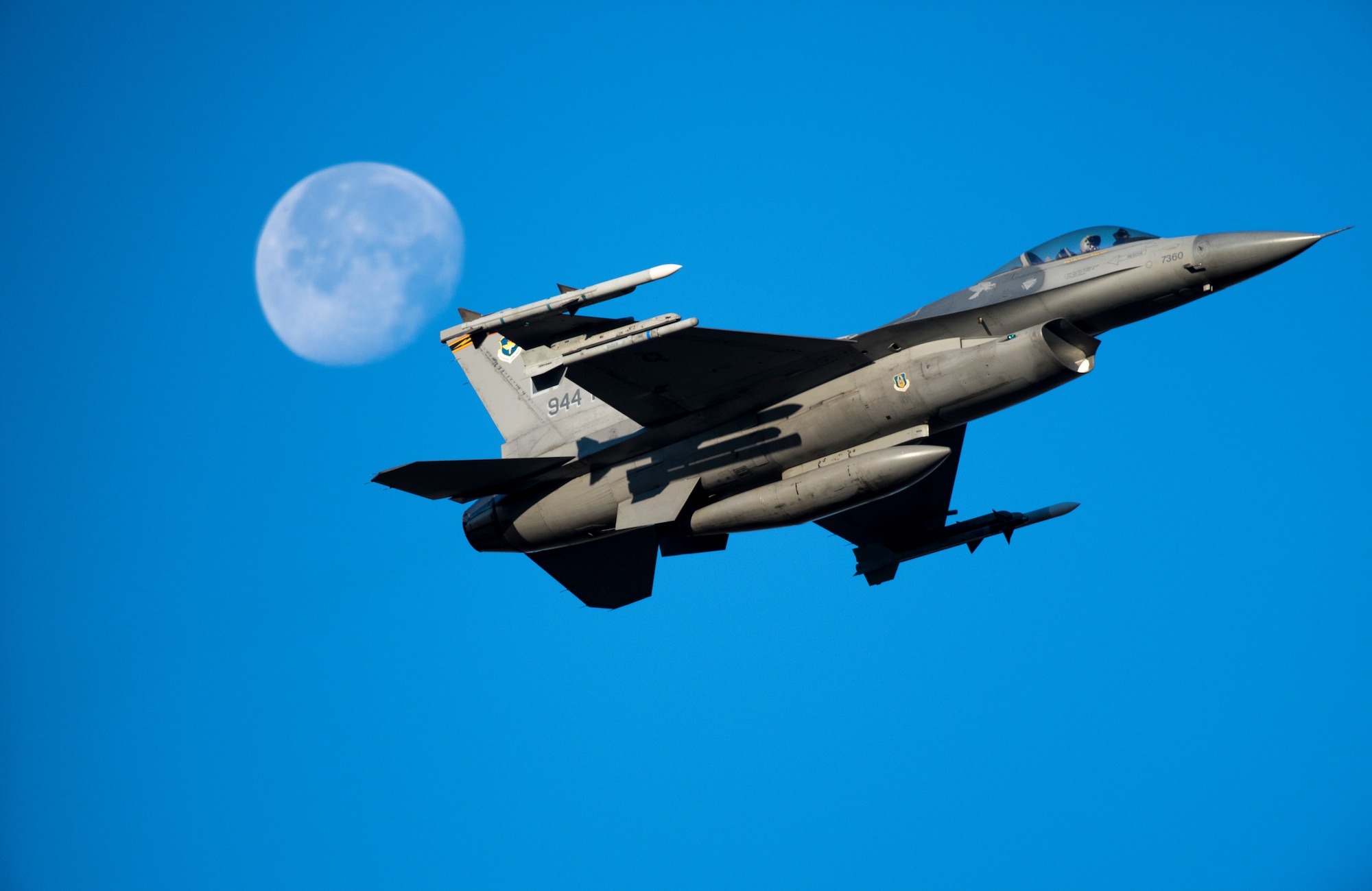 Photo of an F-16 day flight with a faded moon in the background