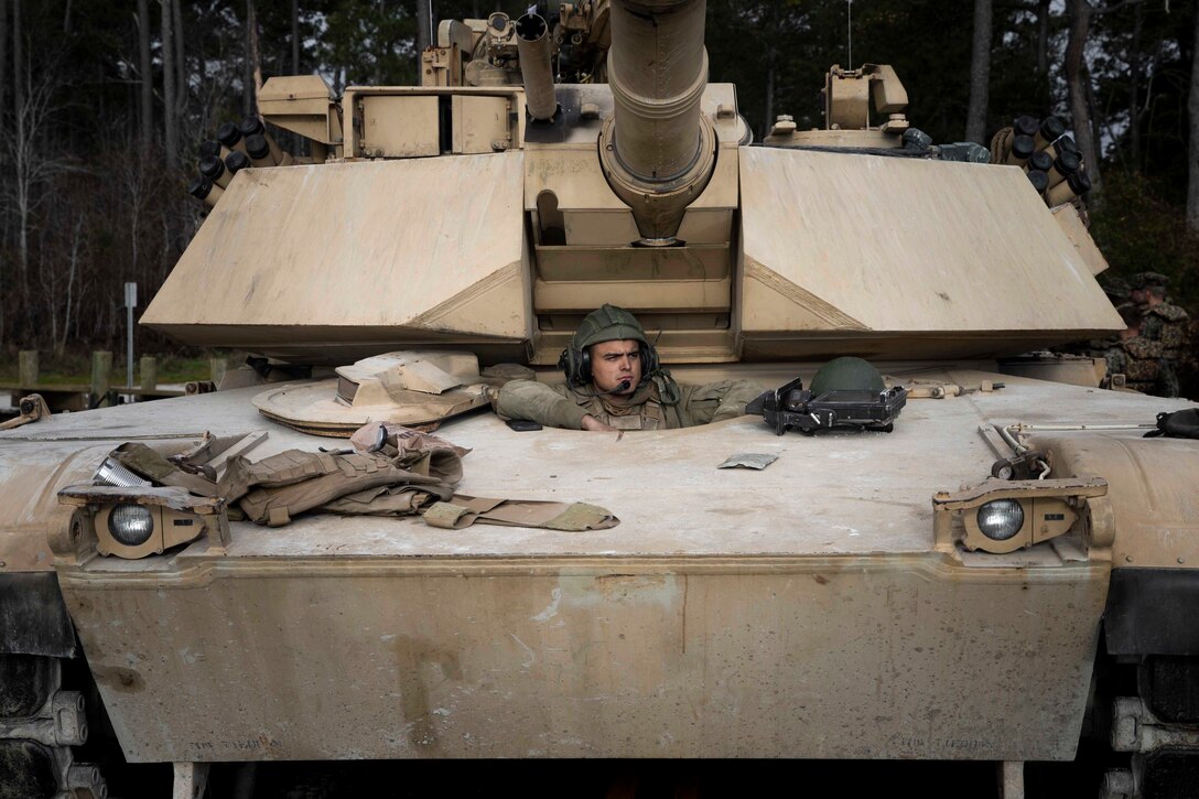 A Marine sits inside of a military vehicle.