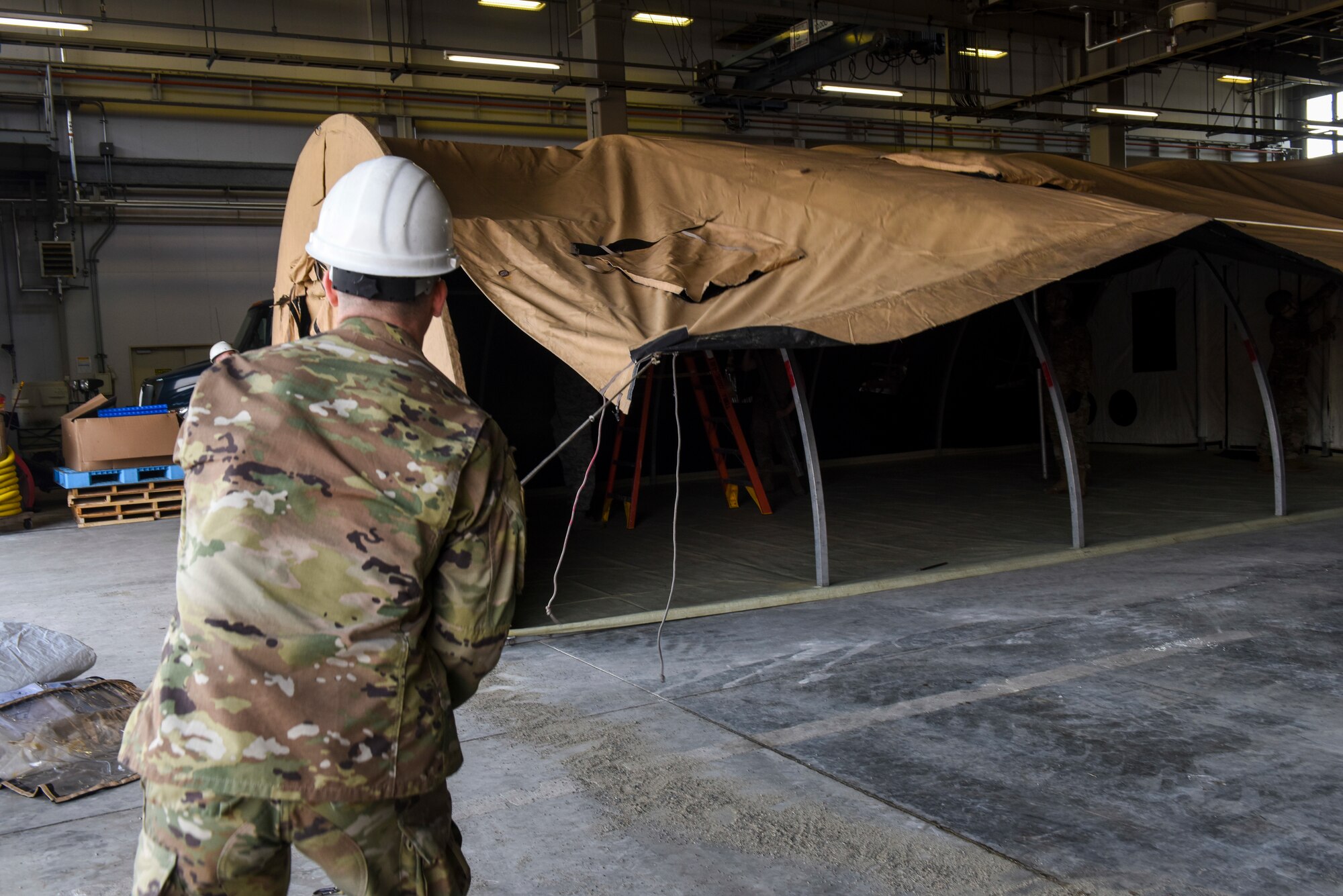 A U.S. Airman pulls the tarp of a small shelter system tent over its frame during an Agile Combat Employment practice capstone event at Misawa Air Base, Japan, March 13, 2020. The ACE concept requires units to deploy small teams, who will be able to build their own shelters, pack their own cargo for shipping, and generally conduct operations from any austere location. (U.S. Air Force photo by Tech. Sgt. Timothy Moore)