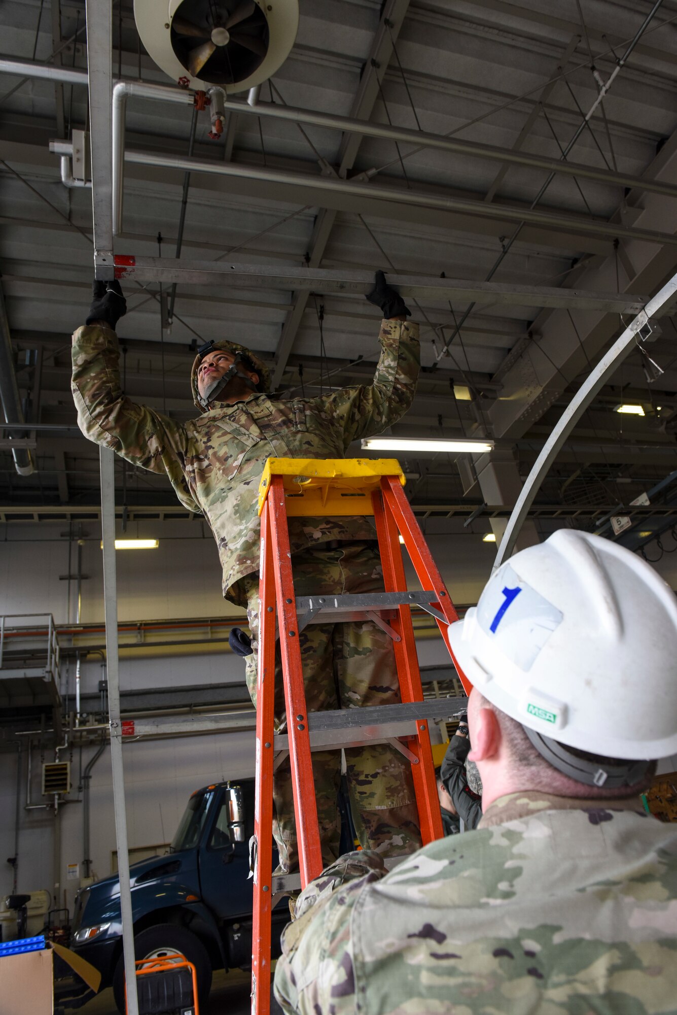 U.S. Air Force Airman Cameron Coughlin, a structures technician with the 35th Civil Engineer Squadron, holds a ladder for Senior Airman Kenneth Brown, an alarm monitor with the 35th Security Forces Squadron, as he connects the beams on a small shelter system tent during an Agile Combat Employment practice capstone event at Misawa Air Base, Japan, March 13, 2020. The ACE concept requires units to be able to deploy small teams to austere locations. As such, Airmen are training so they can assist in completing tasks outside of their normal career functions. (U.S. Air Force photo by Tech. Sgt. Timothy Moore)