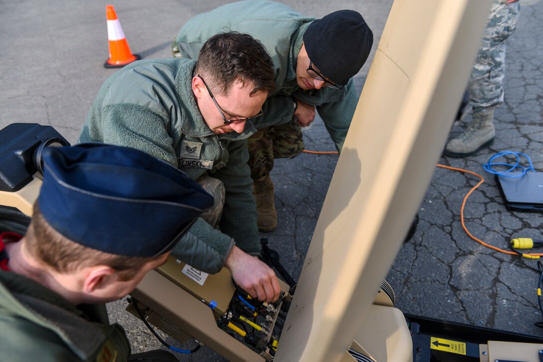 U.S. Air Force Staff Sgt. Barry Zielinski, a cyber transportation supervisor with the 35th Communications Squadron, shows Capt. Joseph Holloway, a pilot with the 13th Fighter Squadron, and 1st Lt. Jordan Garcia, an assistant unit deployment manager with the 14th Fighter Squadron, how to set up a Hawkeye III antenna at Misawa Air Base, Japan, March 13, 2020. Zielinski showed the two officers how to set up the antenna as part of a practice capstone event for the Agile Combat Employment training for Misawa Airmen. (U.S. Air Force photo by Tech. Sgt. Timothy Moore)