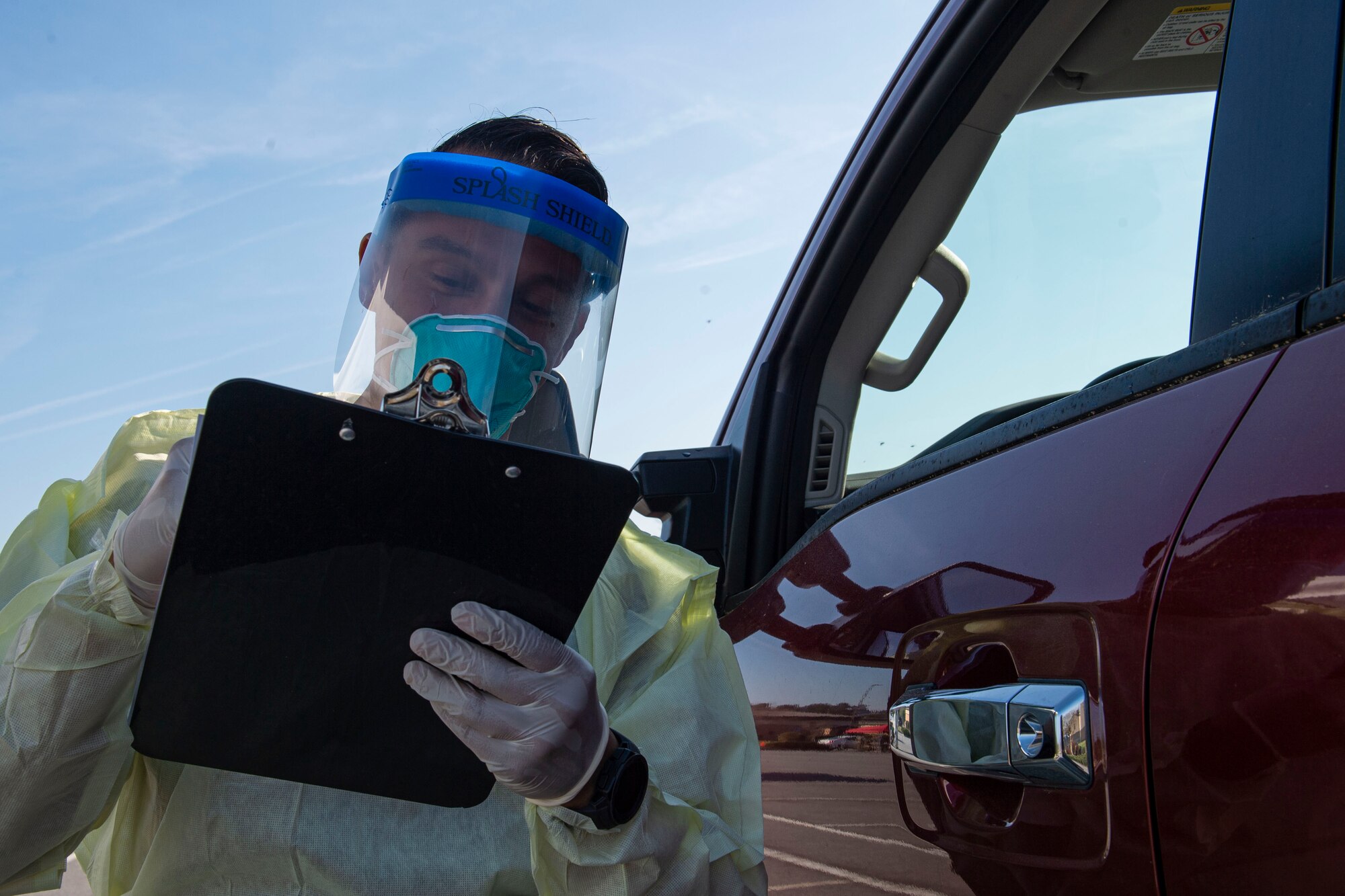 Photo of an Airman asking an active duty Airman questions during a drive-through health screening.