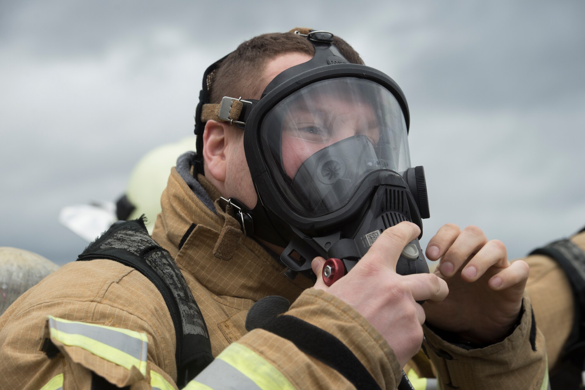 Photo of firefighter putting on gas mask.