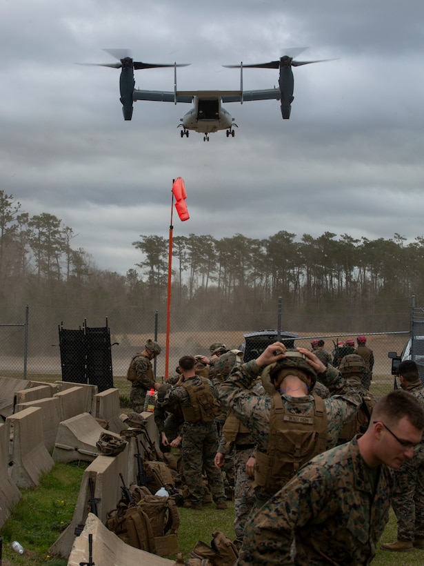 Marines with Expeditionary Operations Training Group prepare their gear while a V-22 Osprey with the Japan Ground Self-Defense Force lands at Tactical Landing Zone Vulture, Stone Bay, Camp Lejeune, North Carolina, Feb. 12, 2020. The JGSDF trained with Marine Medium Tiltrotor Training Squadron 204 to expand mission capabilities. (U.S. Marine Corps photo by Cpl. Ethan Pumphret)