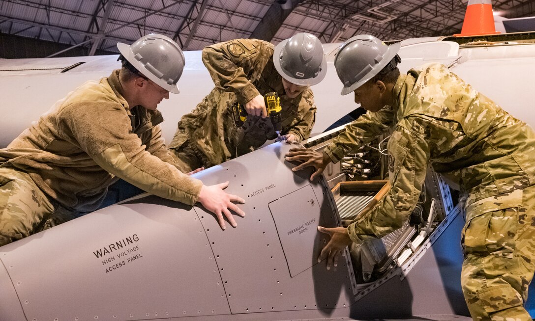 Senior Airman Brian Dawson, left, and Airman 1st Class Quantavius Martin, right, hold down a pylon panel as Senior Airman Mike Carlucci installs fasteners March 17, 2020, at the C-5 Isochronal Inspection Dock on Dover Air Force Base, Delaware. All three 436th Maintenance Squadron aircraft maintenance journeymen practiced social distancing, as much as possible, while performing maintenance on the C-5M Super Galaxy. (U.S. Air Force photo by Roland Balik)