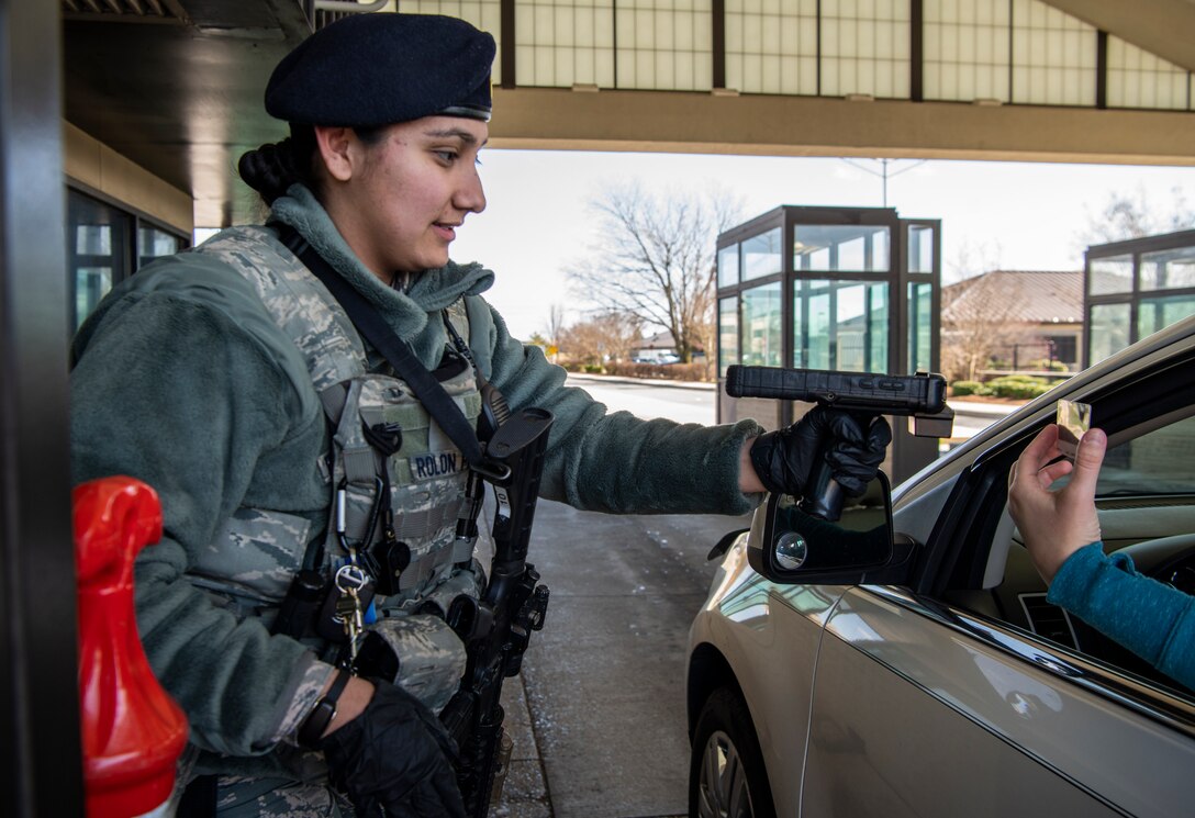 Airman 1st Class Guadalupa Rolon Pena, 436th Security Forces Squadron response force member, scans a Common Access Card March 17, 2020, at Dover Air Force Base, Delaware. Members accessing the base will follow new gate procedures by holding their CAC with the back barcode facing the defender. The defender will then scan the back of the CAC and inform the member when they allowed to enter. (U.S. Air Force photo by Senior Airman Christopher Quail) (This photo has been altered for security purposes by blurring out identification badges)