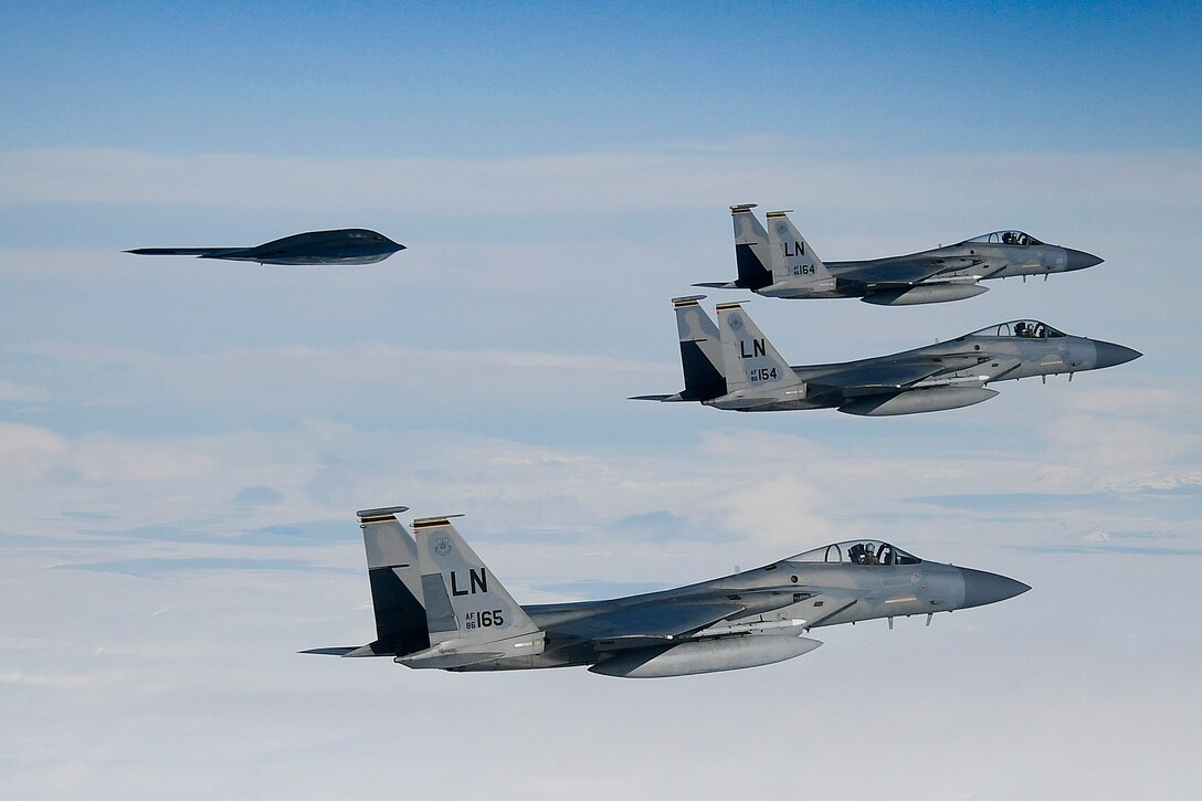 Four military aircraft fly together across the sky.