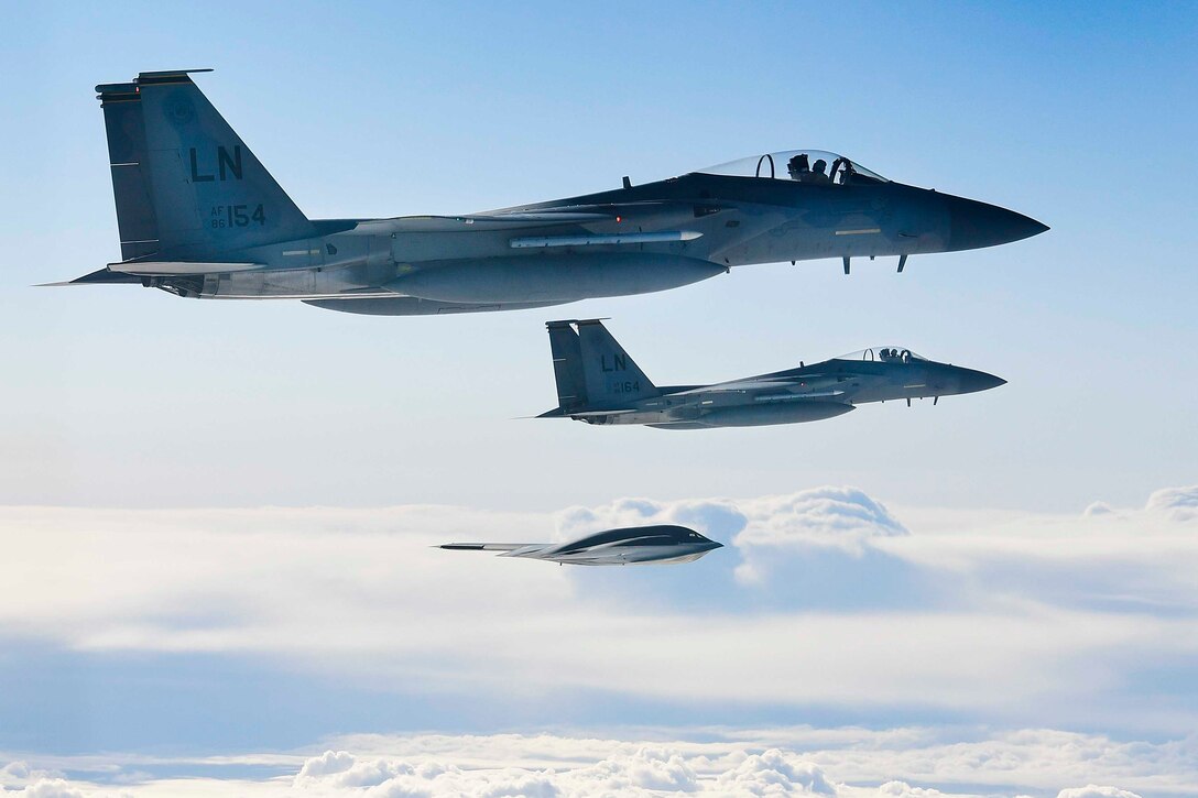 Three military planes fly in the sky.