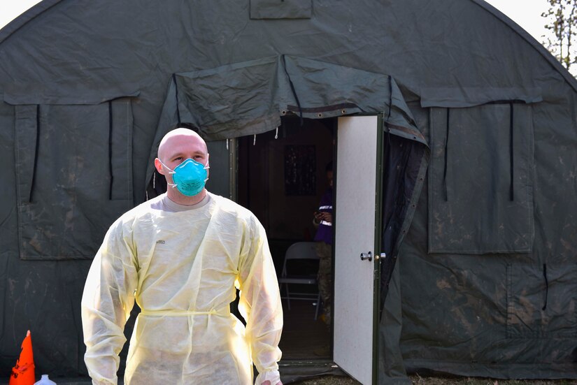 A photo of a medical personnel walking out of a tent.