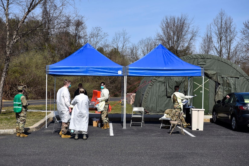 A photo of medical personnel working under a tent.
