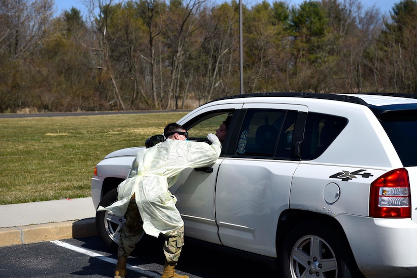 Photo of an Airman administering a COVID-19 test to a patient in their car.