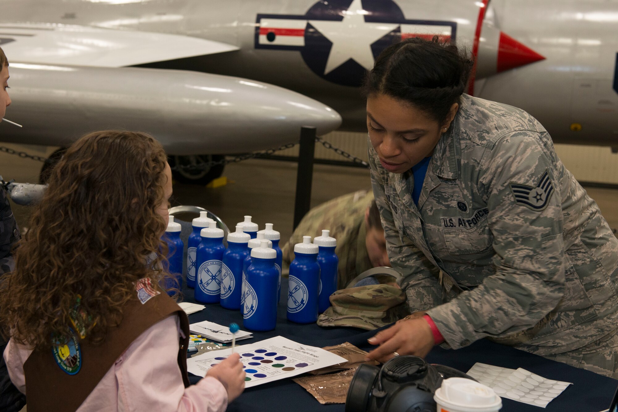 Air Force Staff Sgt. Nathalie Jean-Louis speaks with a girl about the Air National Guard at the annual "Women Take Flight" event held at the New England Air Museum, Windsor Locks, Connecticut, March 7, 2020. "Women Take Flight" is targeted toward girls who are interested in avionics and other STEM related fields.(U.S. Air National Guard photo by Tech. Sgt. Tamara R. Dabney)