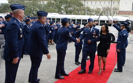 Master Sgt. Marquise Heard, 367th Recruiting Group, Robins Air Force Base, Georgia, and his wife Sofia walk through the guantlet as he is recognized as a Blue Suitor in front of headquarters Air Force Recruiting Service, Joint Base San Antonio- Randolph, Texas. (Air Force photo/Master Sgt. Chance Babin)