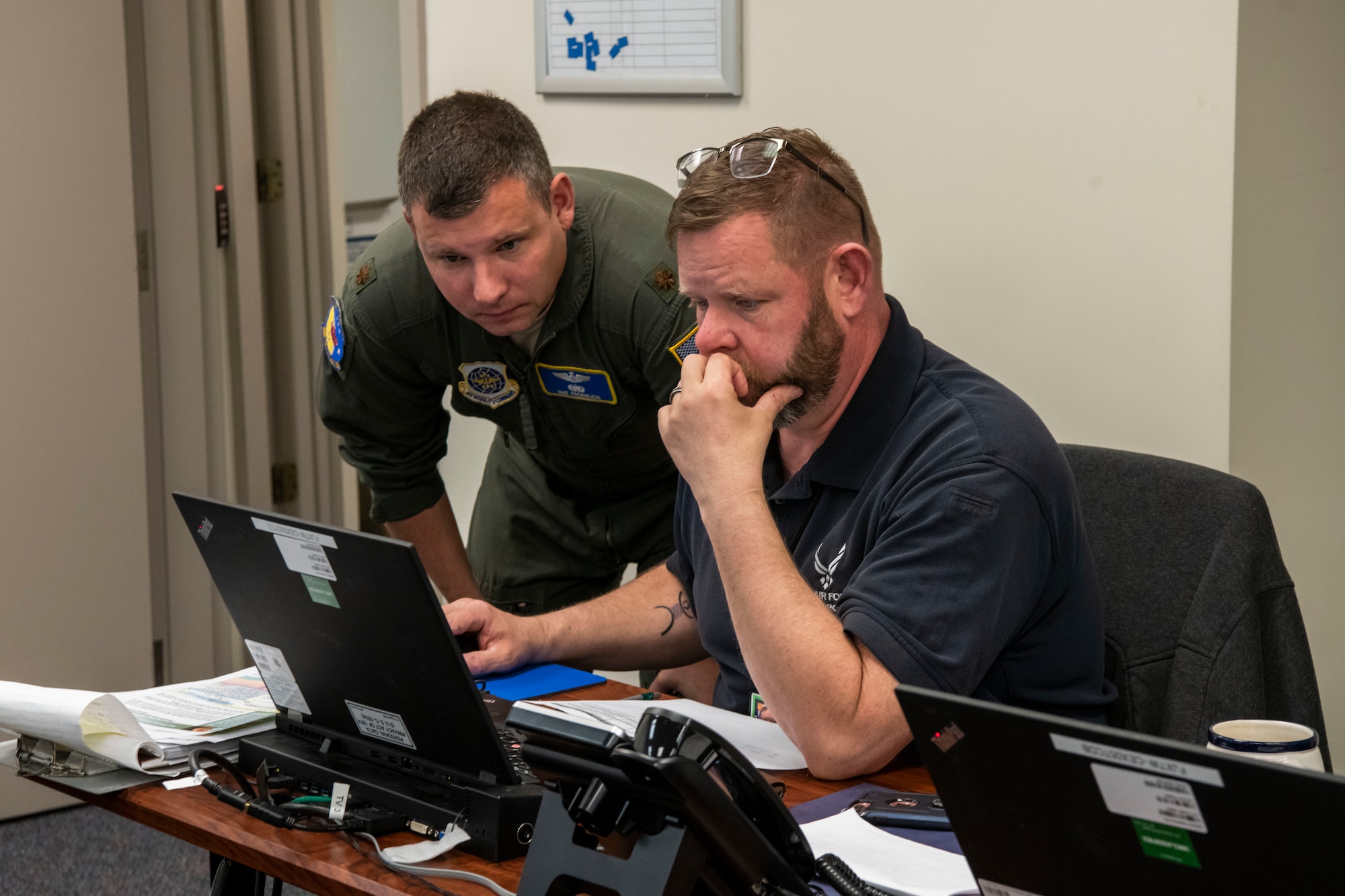 Maj. Mathew Froehlich (left), 3rd Airlift Squadron assistant director of operations, and Arnold Maas, 436th Civil Engineer Squadron emergency manager, look over documents March 16, 2020, at Dover Air Force Base, Delaware. They are both part of the Crisis Battle Staff designated to protecting the health of our communities and will continue to monitor and assess the situation. (U.S. Air Force photo by Senior Airman Christopher Quail)
