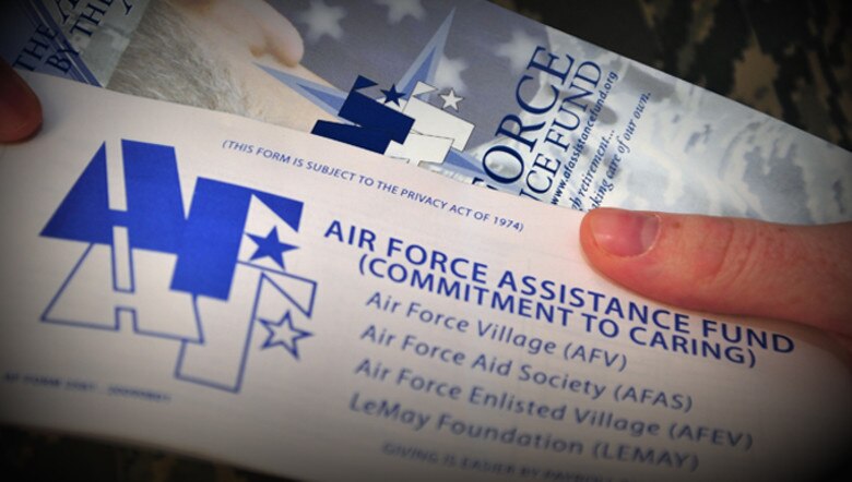 Close up of two people holding brochures for the Air Force Assistance Fund