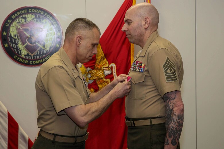 Maj. Gen. Matthew G. Glavy, Marine Corps Forces Cyberspace Command and Joint Task Force Ares commander, pins a Legion of Merit medal on Sgt. Maj. Daniel L. Krause during a relief and appointment ceremony in Lasswell Hall, Fort Meade, Maryland, Mar. 19, 2020. Krause relinquished his duties as the sergeant major of MARFORCYBER while Sgt. Maj. Jay D. Williamson was appointed to fill the role. (Department of Defense photo by Joseph Wilbanks)