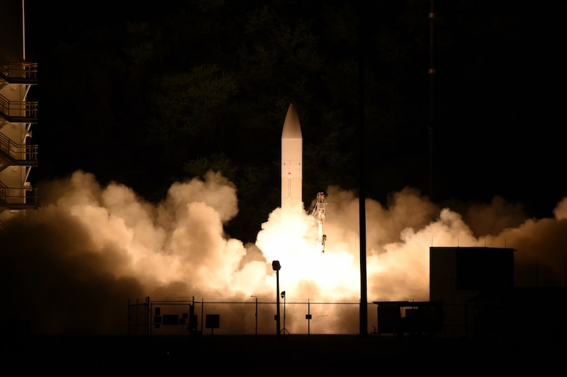 A nighttime missile launch with black sky and white smoke surrounding the missile.