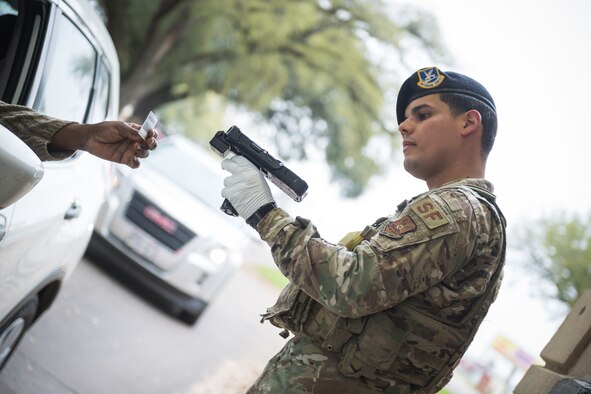 Senior Airman Abner Munoz Rios, 2nd Security Forces Squadron installation patrolman, scans an identification card at Barksdale Air Force Base, La., March 16, 2020. Due to health concerns, security forces modified entry procedures to limit interpersonal contact. (U.S. Air Force photo by Senior Airman Lillian Miller)