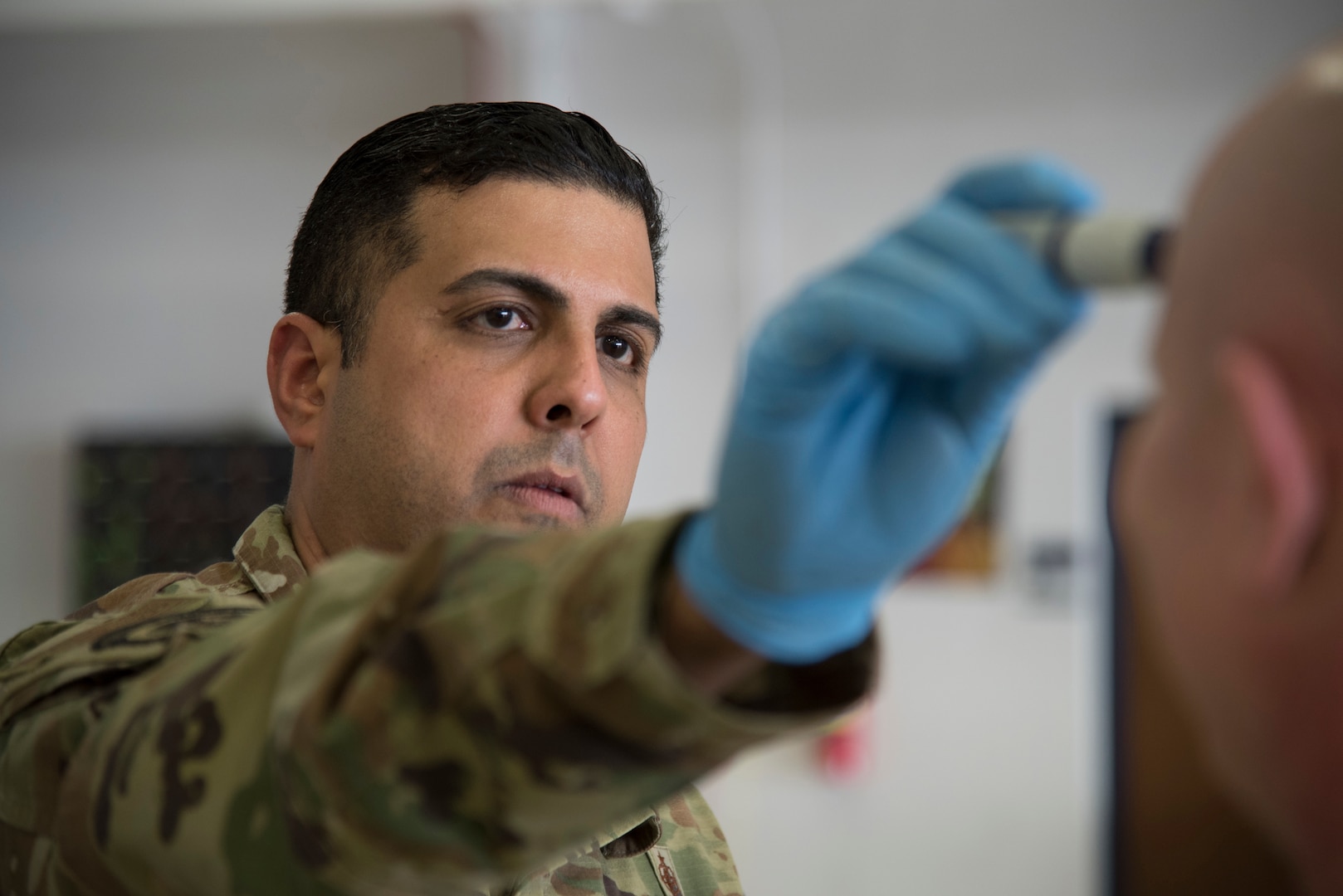 New Jersey Air National Guard Tech. Sgt. Emilio E. Gonzalez, a 108th Medical Group public health technician, checks the temperature of a Security Forces Airman at Joint Base McGuire-Dix-Lakehurst, N.J., March 19, 2020. The medical group screened members for possible fever, a common symptom of COVID-19, before being put on state active duty orders