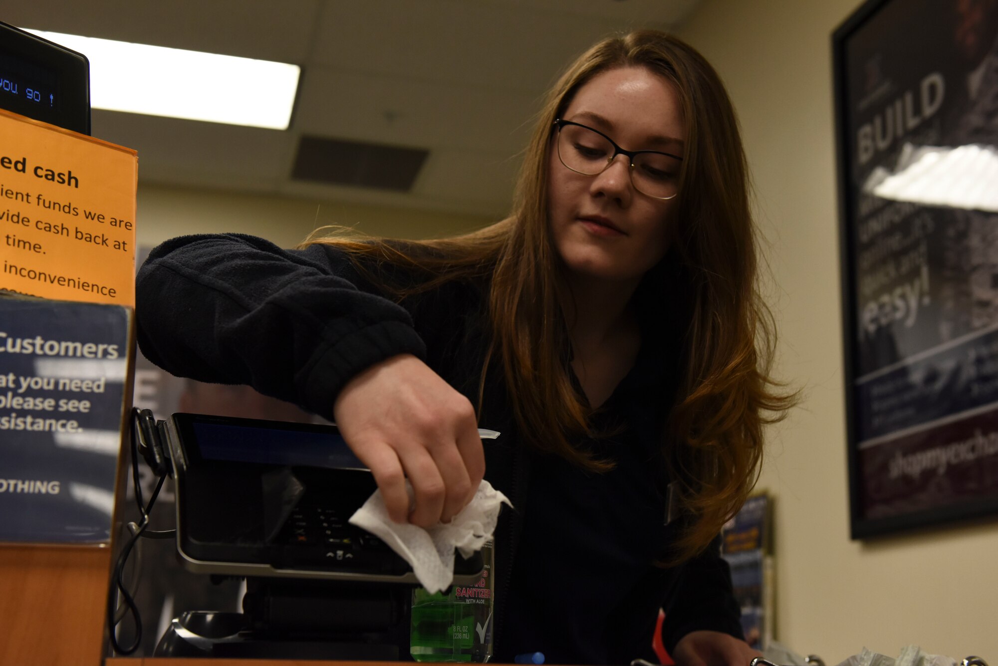 Rebecca Piper, Military Clothing sales associate, cleans off the card machine with cleansing wipes at Whiteman Air Force Base, Missouri, March 19, 2020. Military Clothing will clean off all their counters and card machines after every customer. (U.S. Air Force photo by Senior Airman Alexandria Lee)