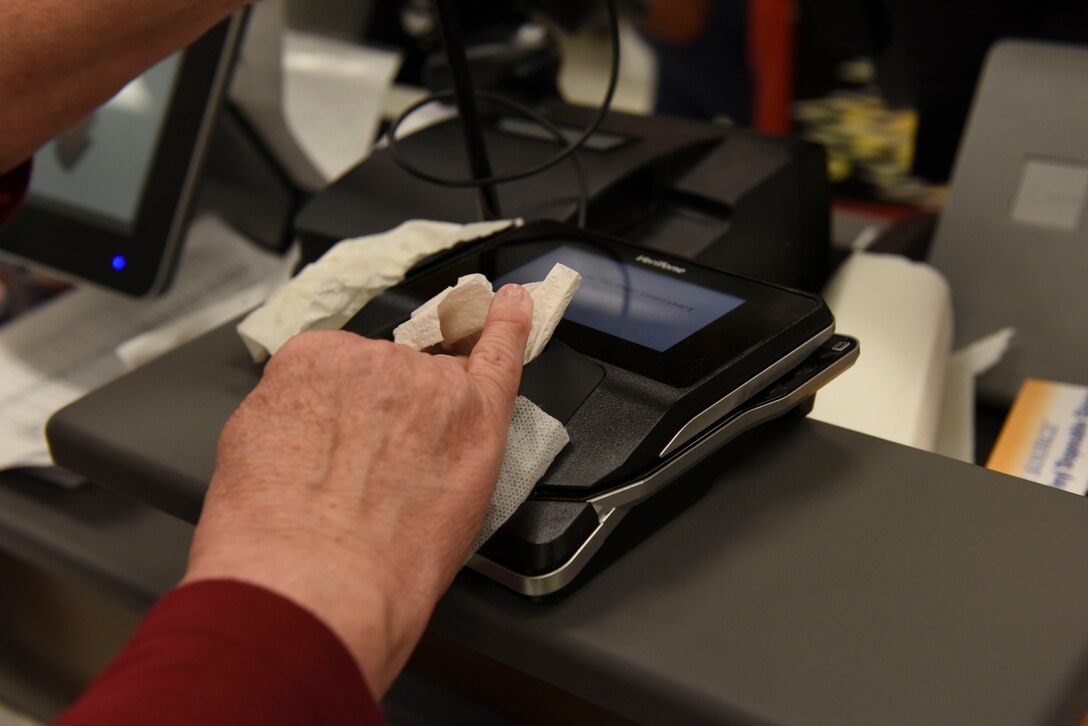 Edna Roberson, Whiteman Air Force Base Commissary assistant store director, sanitizes the card machine at Whiteman Air Force Base, Missouri, March 19,2020.  Whiteman Air Force Base Commissary is committed to deep cleaning all the shelves before opening and after closing time, also wiping down all self-check out after each customer.(U.S. Air Force photo by Senior Airman Alexandria Lee)