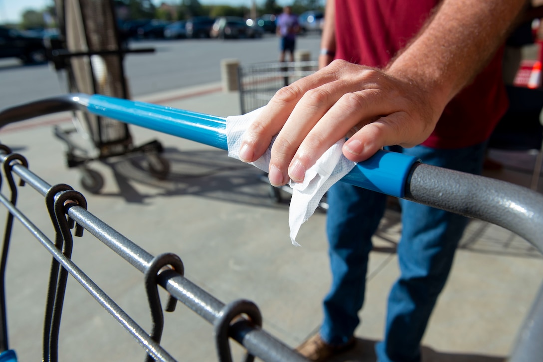 Photo of a customer sanitizing a cart in front of the commissary.