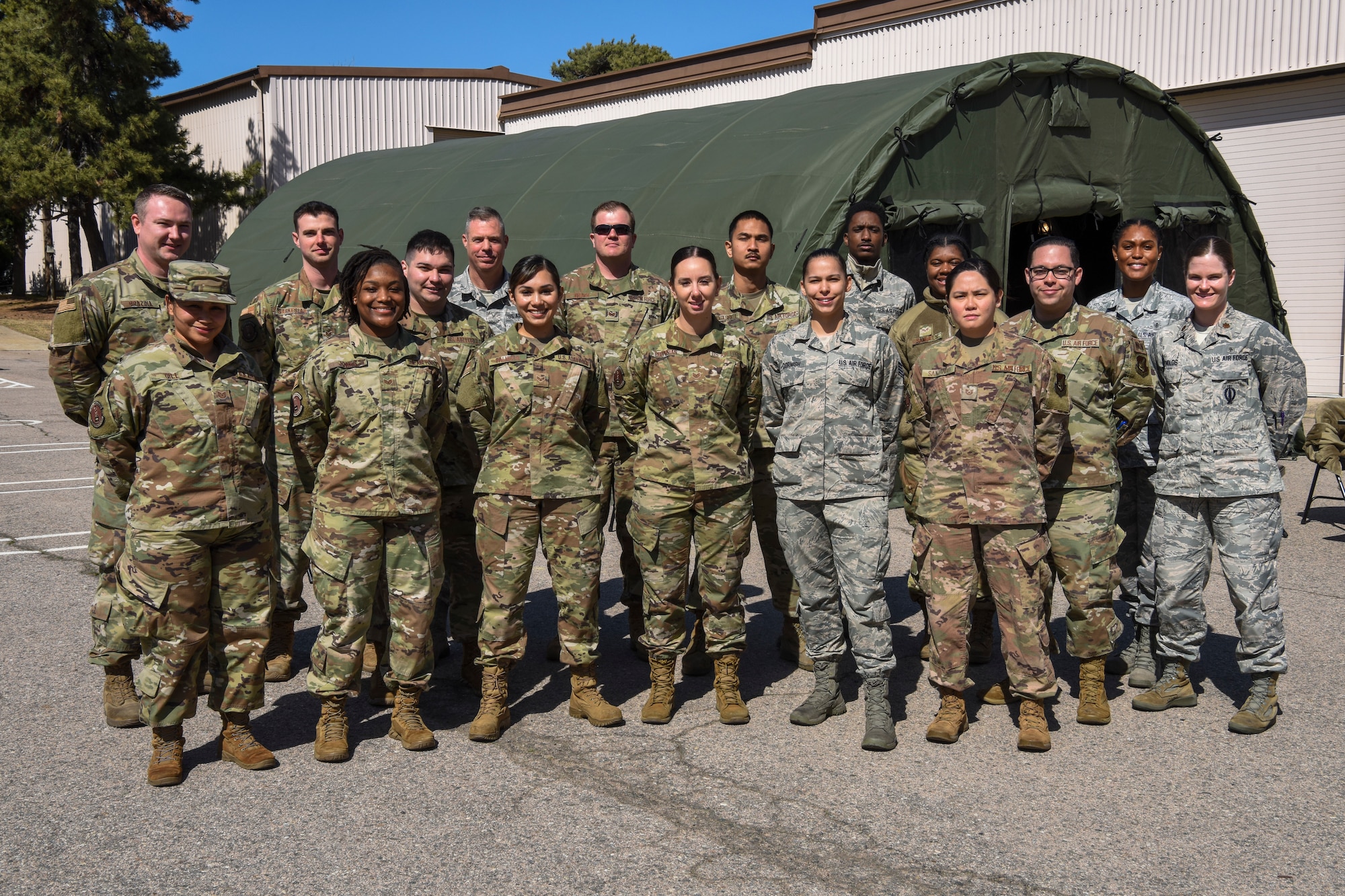 Personnel assigned to the 8th Medical Group pose for a photo in front of a medical screening tent at Kunsan Air Base, Republic of Korea March 19, 2020. The 8th Medical Group took proactive and precautionary measures amid the COVID-19 pandemic by standing up a screening tent outside of the clinic for service members who have recently returned to Kunsan from international travel. (U.S. Air Force photo by Senior Airman Jessica Blair)