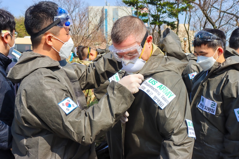 Soldier assists soldier with protective equipment