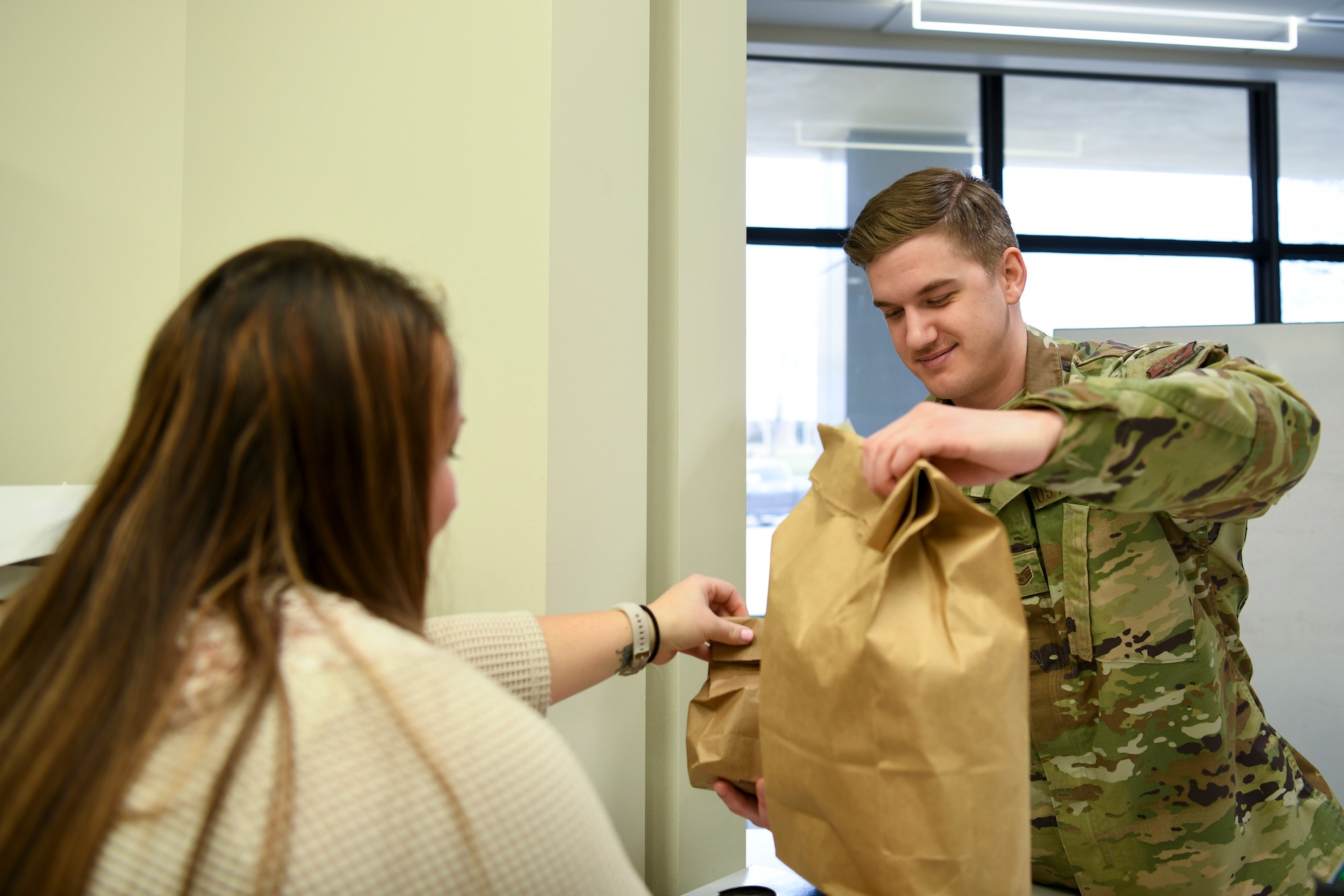 Natalie McCoy, left, a 509th Operational Medical Readiness Squadron base operational support team manager, passes a bag of prescriptions to U.S. Air Force Staff Sgt. Nathan Jones, a 509th Operational Medical Readiness Squadron bioenvironmental technician and pharmacy augmentee, for delivery to a patient outside at Whiteman Air Force Base, Missouri, March 20, 2020. The medical group’s pharmacy implemented curbside pickup pharmacy procedures. The new service allows individuals with called-in refills and activated prescriptions to park in a designated parking spots and have their prescriptions delivered to the car. This procedure is part of the effort to limit visiting the facility. (U.S. Air Force photo by Staff Sgt. Dylan Nuckolls)