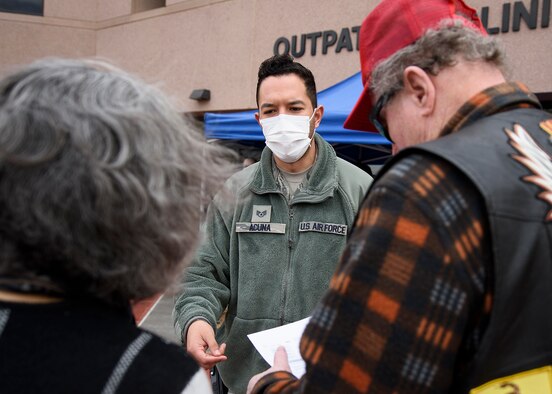An Airman hands paper providing information to civilians.
