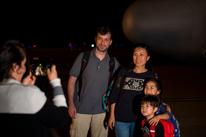 A family of passengers pose in front of a C-130 Hercules at Joint Base Charleston, S.C., March 20, 2020.