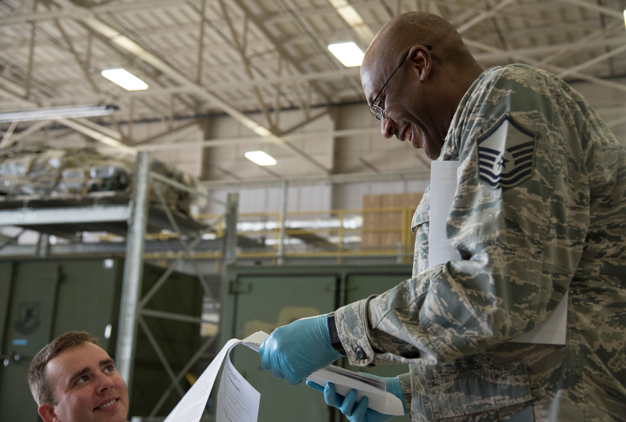 Photo of an Airman collecting paperwork from another Airman.