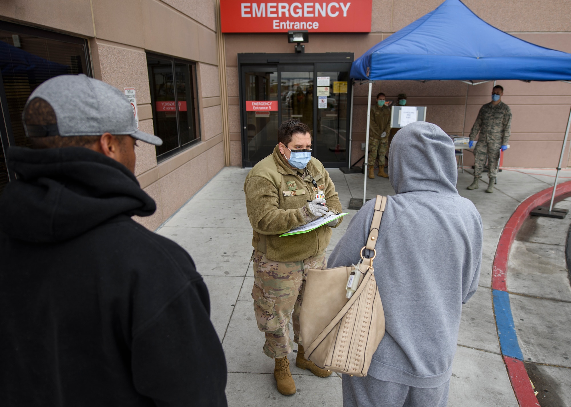 An Airman writes down information from two civilians.