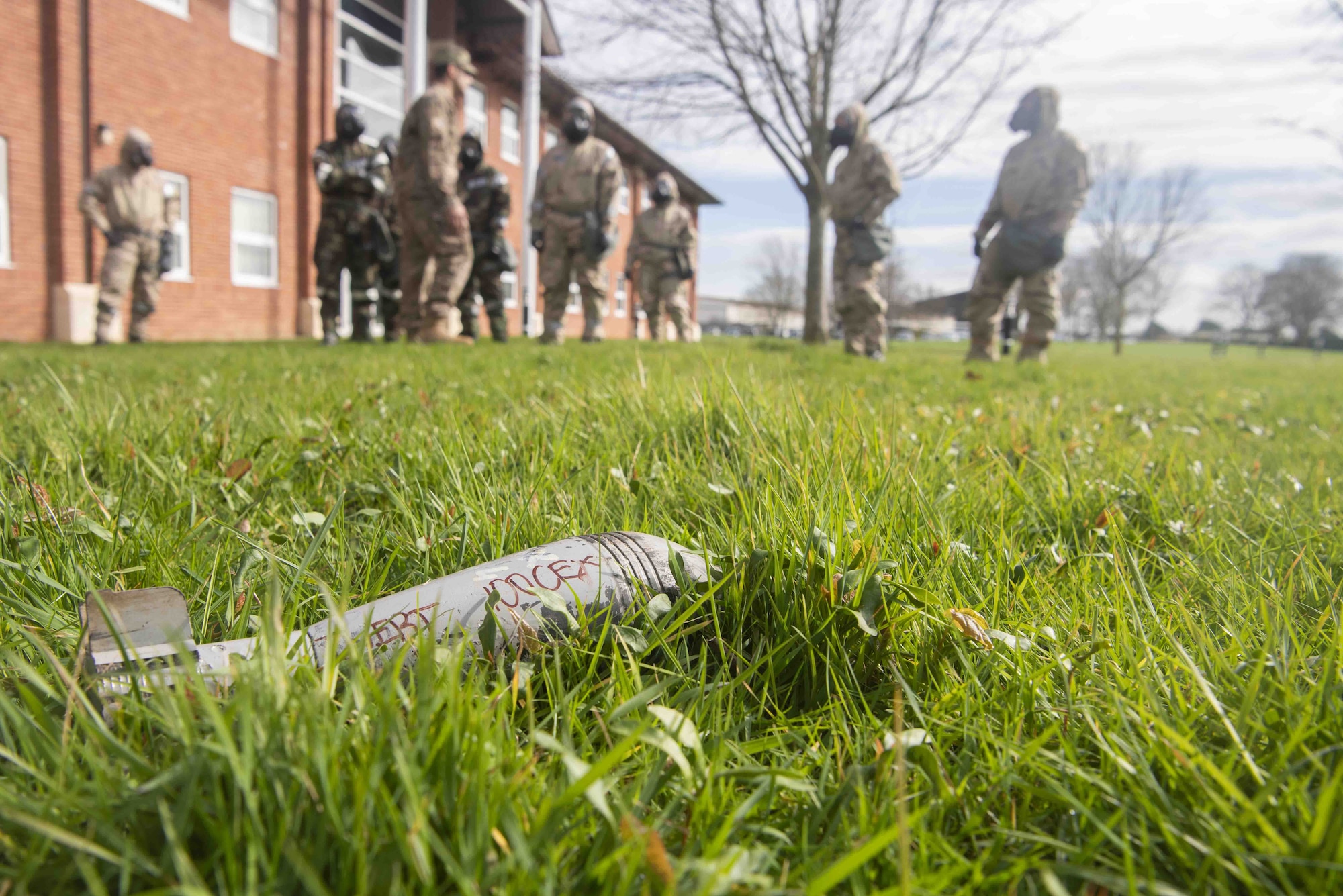 Team Mildenhall Airmen and an instructor from the 100th Civil Engineer Squadron emergency management shop pause before an inert unexploded ordinance as part of a chemical, biological, radiological and nuclear defense skills class March 17, 2020, at RAF Mildenhall, England. Emergency management Airmen help maintain base readiness by teaching CBRN skills to Airmen serving at home station as well as in deployed environments. (U.S. Air Force photo by Airman 1st Class Joseph Barron)