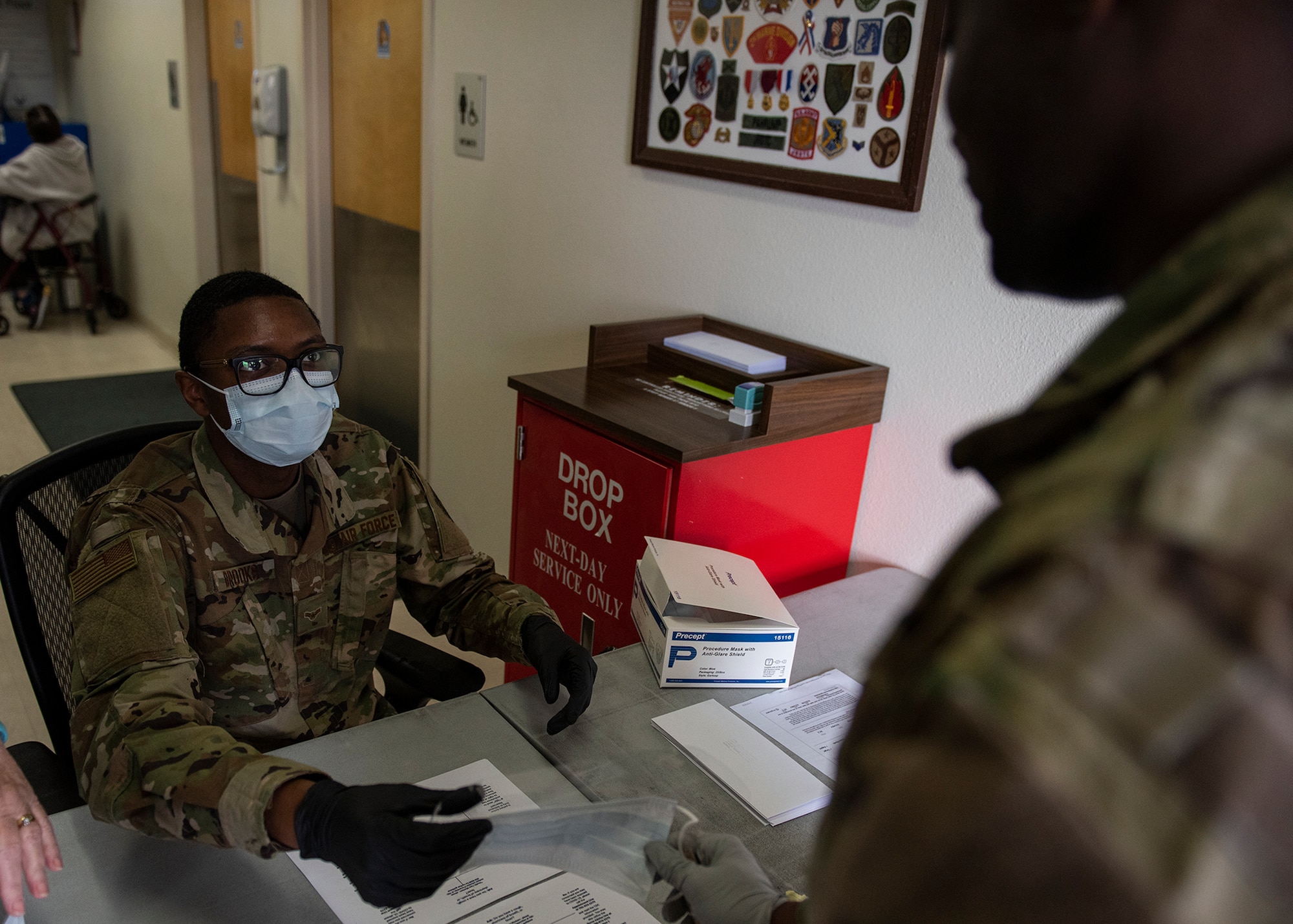 An Airman hands another Airman a mask.