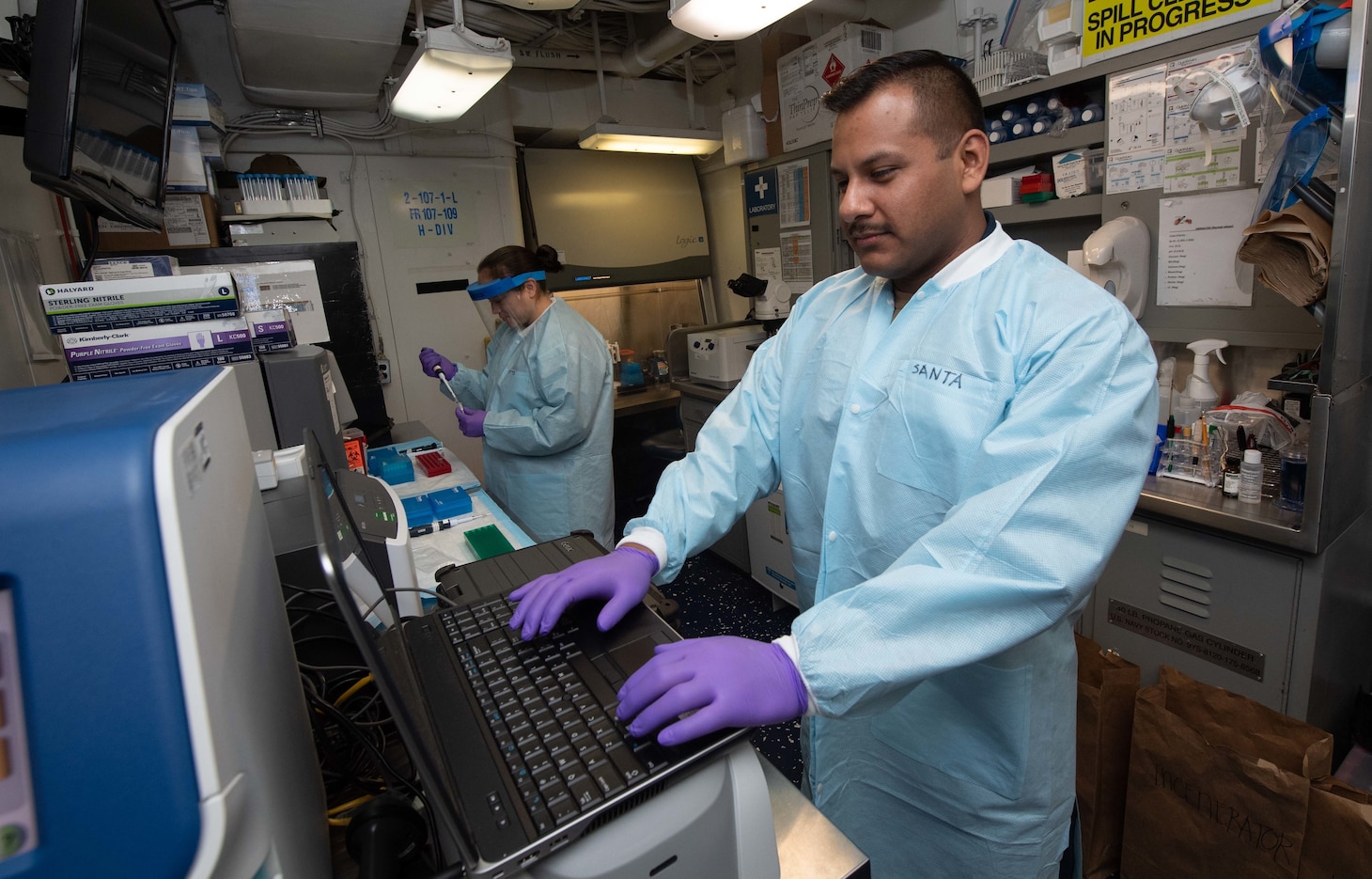 PHILIPPINE SEA (March 19, 2020) Hospital Corpsman 1st Class Ernesto Santa Ana, right, and Hospital Corpsman 2nd Class Maria F. Potts-Szoke, work in Naval Medical Research Center's mobile laboratory aboard the aircraft carrier USS Theodore Roosevelt (CVN 71) March 19, 2020. The Theodore Roosevelt Carrier Strike Group is on a scheduled deployment to the Indo-Pacific.