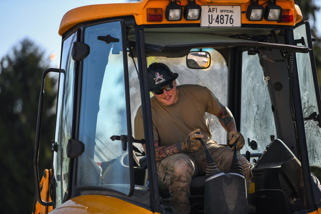 U.S. Air Force Senior Airman Joshua Carney, 31st Civil Engineer Squadron heavy equipment operator, steers a backhoe at Aviano Air Base, Italy, March 23, 2020. The 31st CES ensures lethality and mission readiness as they adjust manning postures to minimize exposure during the COVID-19 outbreak. (U.S. Air Force photo by Airman 1st Class Ericka A. Woolever)