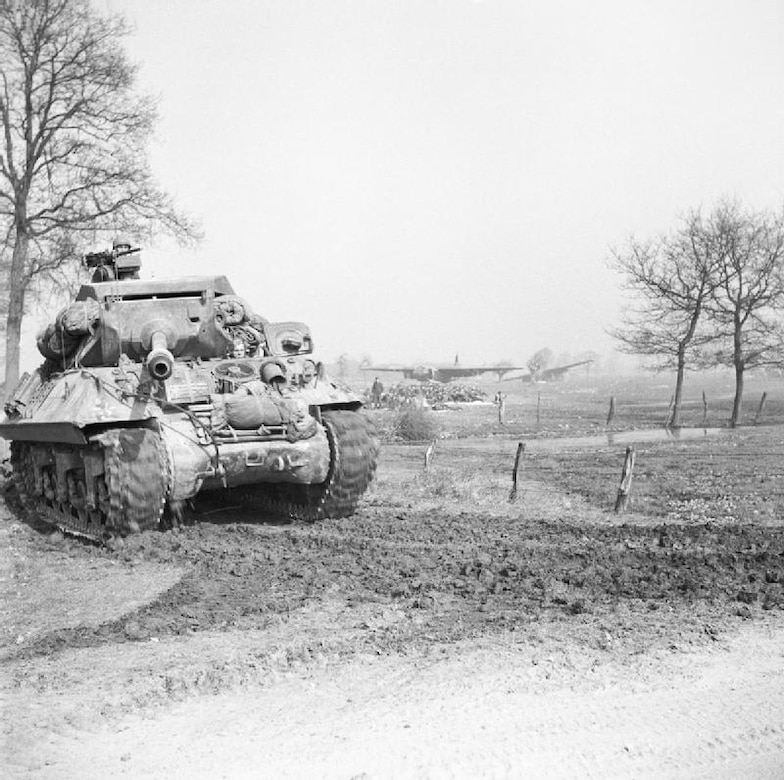 A tank moves down a dirt road.