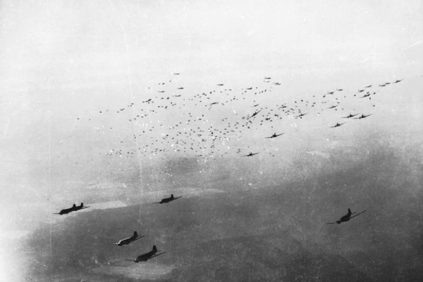 Planes drop paratroopers.