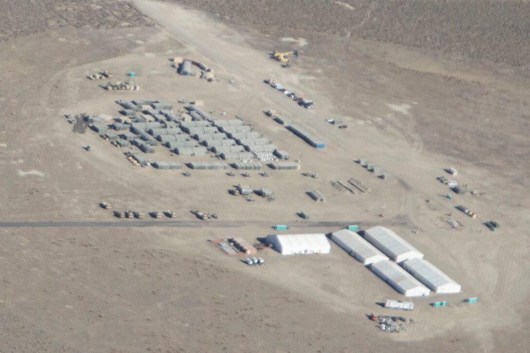 An aerial photo shows a field hospital with many tents spread out across a desert environment.