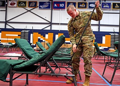 Sgt. Ryan Goyette, 197th Field Artillery Brigade, New Hampshire Army National Guard, sets up one of approximately 250 beds at the Stan Spirou Field House at Southern New Hampshire University in Hooksett, Mar. 23.