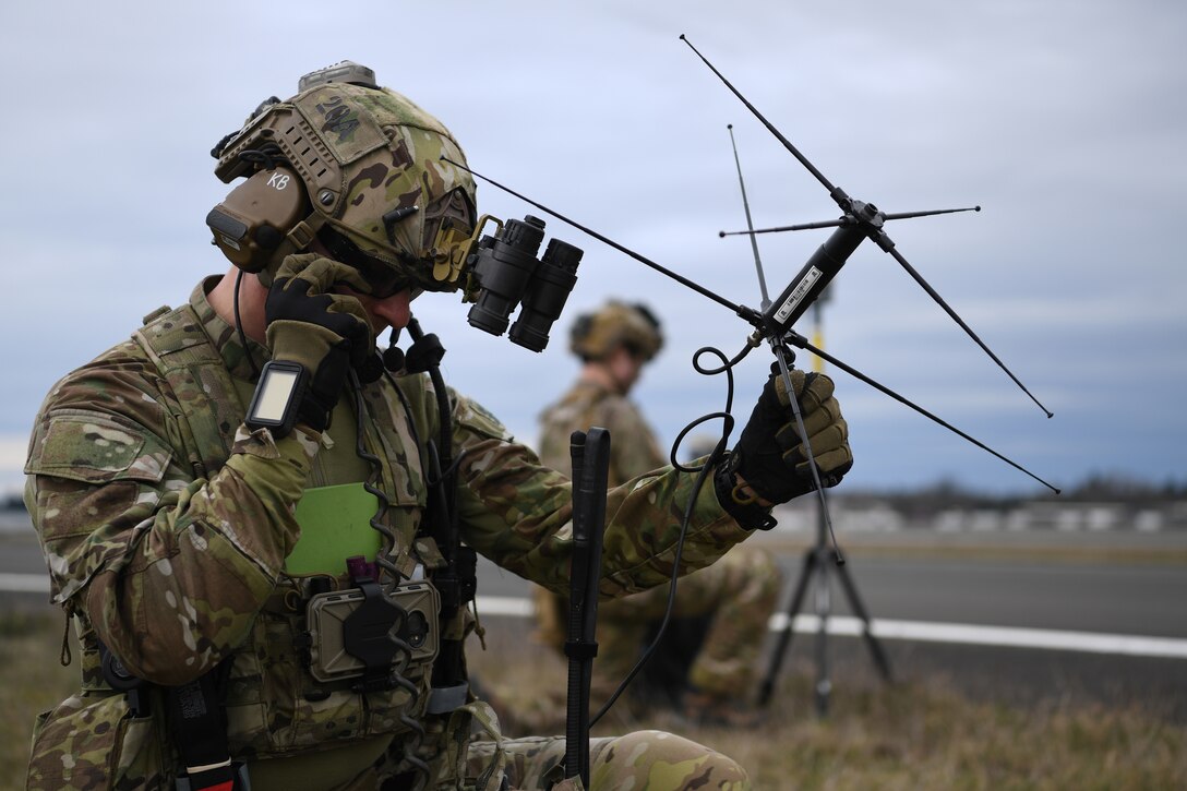 Two airmen hold communication devices,